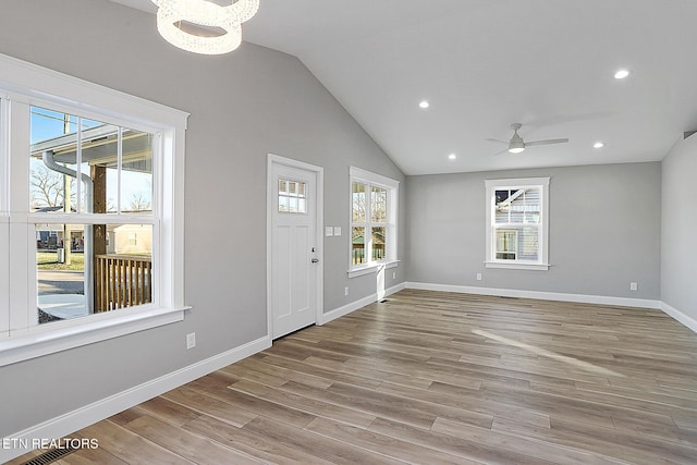 entrance foyer featuring ceiling fan with notable chandelier, vaulted ceiling, and light wood-type flooring