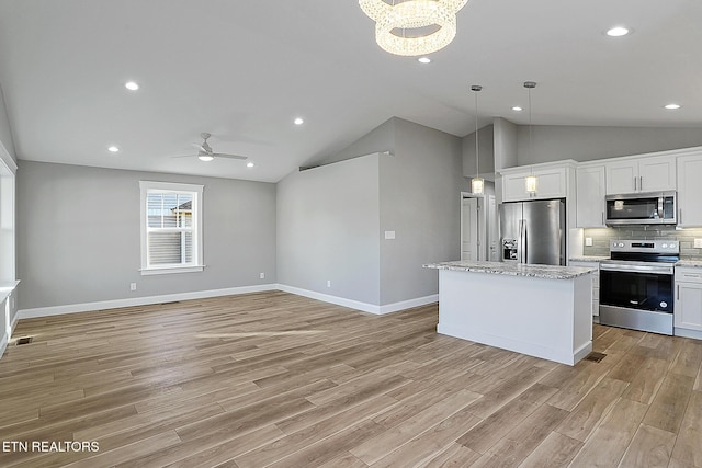 kitchen featuring appliances with stainless steel finishes, backsplash, pendant lighting, a center island, and white cabinetry