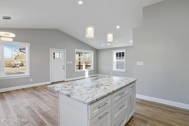 kitchen featuring white cabinets, a kitchen island, vaulted ceiling, and pendant lighting