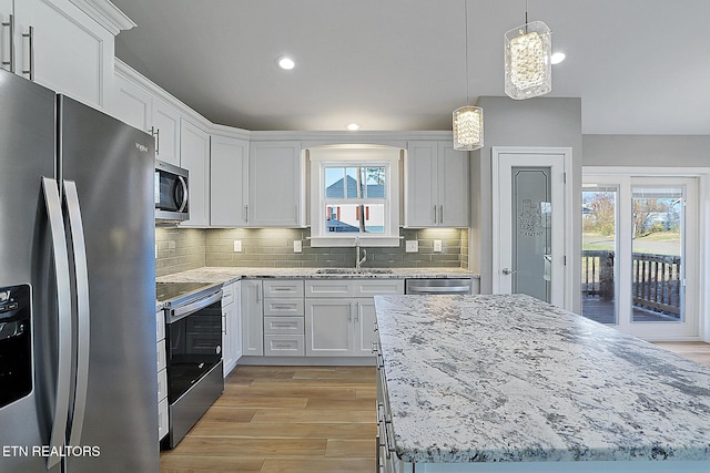 kitchen featuring decorative backsplash, appliances with stainless steel finishes, a wealth of natural light, sink, and white cabinets