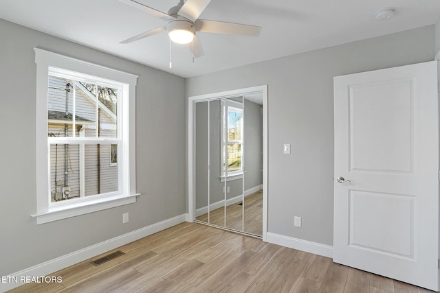 unfurnished bedroom with ceiling fan, a closet, and light wood-type flooring