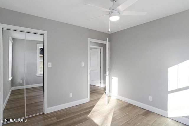 unfurnished bedroom featuring hardwood / wood-style flooring, ceiling fan, and a closet