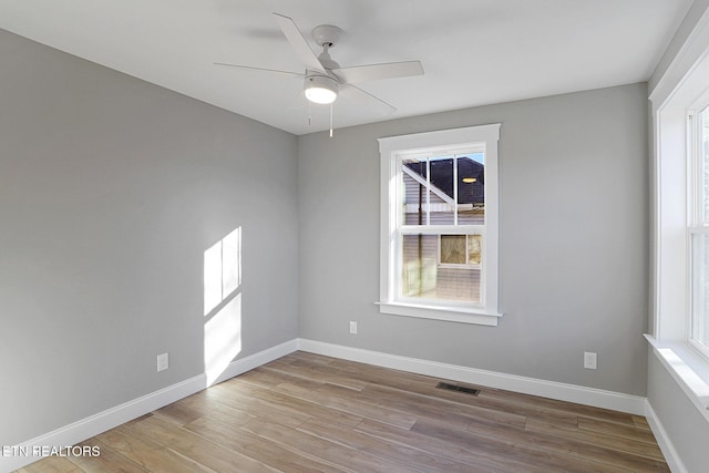 spare room featuring light hardwood / wood-style floors, a wealth of natural light, and ceiling fan