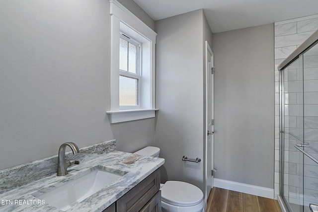 bathroom featuring hardwood / wood-style floors, vanity, toilet, and walk in shower