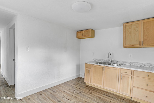 kitchen with light brown cabinetry, sink, and light wood-type flooring