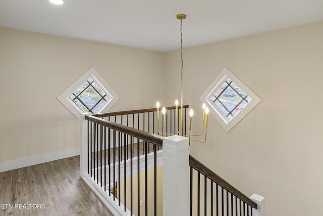 staircase featuring an inviting chandelier and hardwood / wood-style flooring