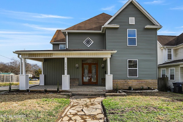 front facade featuring french doors, a front lawn, and covered porch