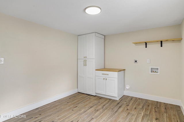 laundry area with hookup for an electric dryer, hookup for a washing machine, light hardwood / wood-style floors, and cabinets