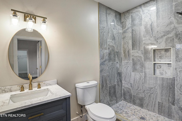 bathroom with vanity, toilet, and a tile shower