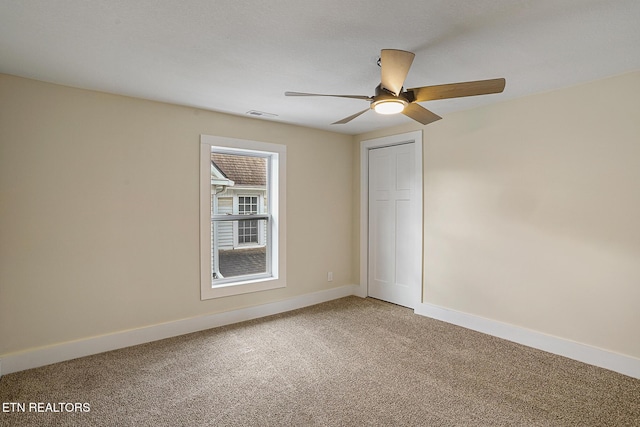 carpeted spare room with ceiling fan