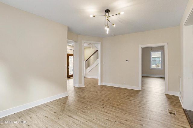 unfurnished room with a chandelier and light hardwood / wood-style floors