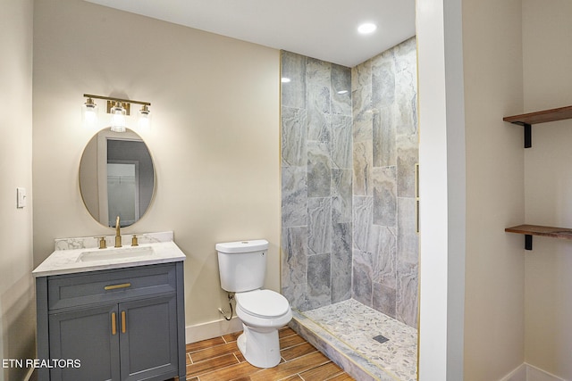 bathroom featuring a tile shower, vanity, and toilet