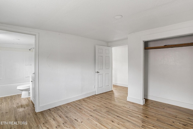 unfurnished bedroom featuring a closet, connected bathroom, and light hardwood / wood-style flooring