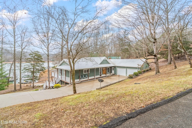 view of front of property with a front yard, a porch, a water view, and a garage