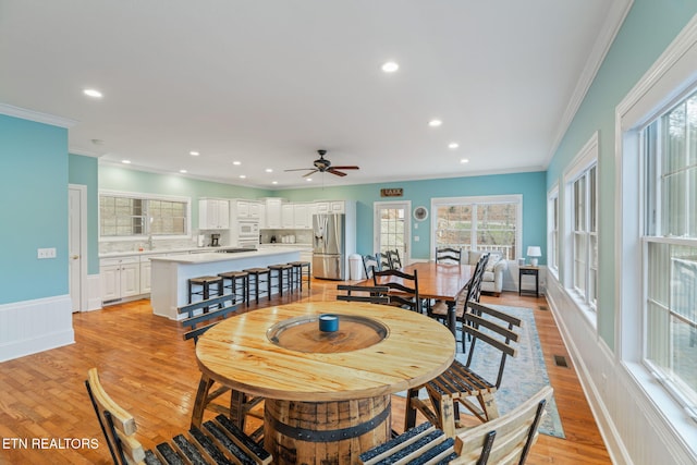 dining room with crown molding, ceiling fan, and light hardwood / wood-style floors