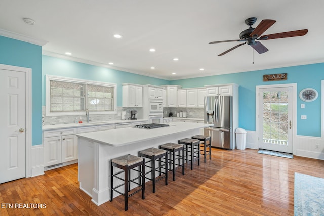 kitchen featuring appliances with stainless steel finishes, a breakfast bar, sink, white cabinets, and a center island