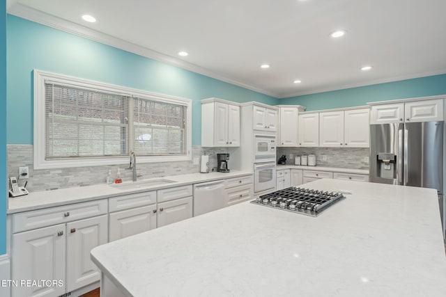 kitchen with white cabinets, sink, ornamental molding, tasteful backsplash, and stainless steel appliances