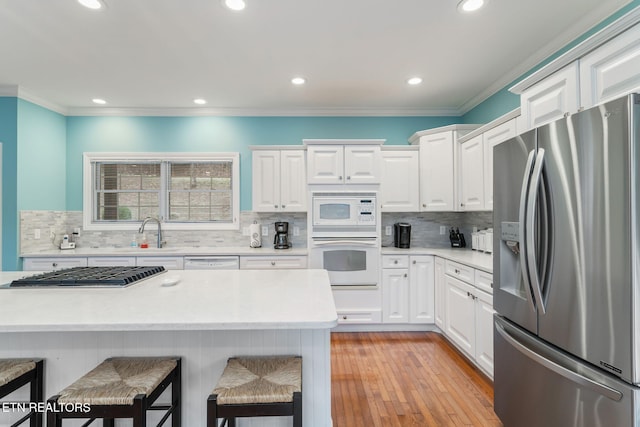 kitchen featuring white cabinets, sink, crown molding, a kitchen bar, and stainless steel appliances