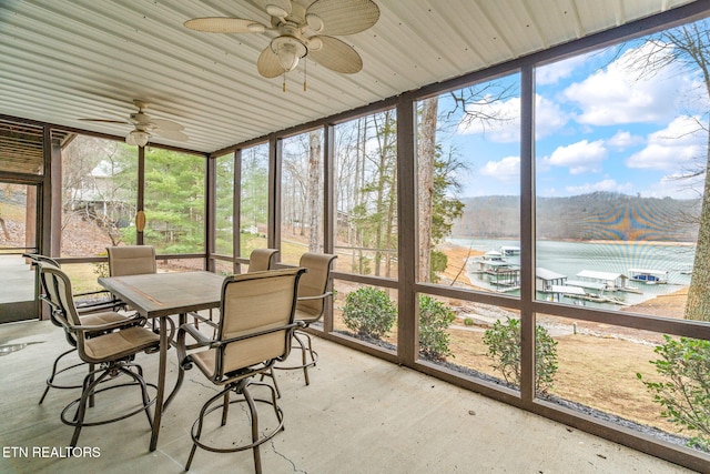 sunroom / solarium featuring a water view, plenty of natural light, and ceiling fan