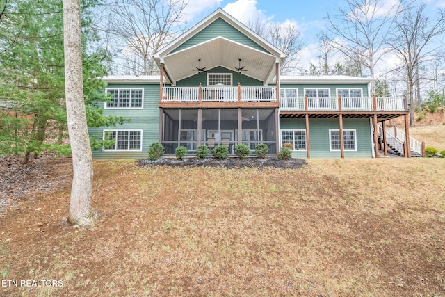 rear view of house with a sunroom, ceiling fan, and a yard