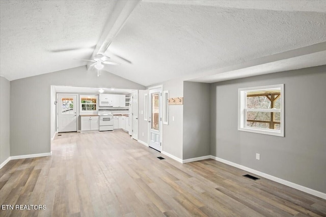 unfurnished living room featuring vaulted ceiling with beams, ceiling fan, and light hardwood / wood-style flooring