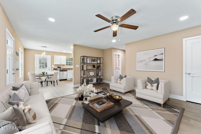 living area with light wood-style flooring, baseboards, a ceiling fan, and recessed lighting