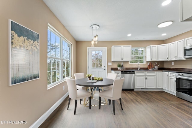 kitchen featuring baseboards, dark wood-style flooring, a sink, appliances with stainless steel finishes, and dark countertops