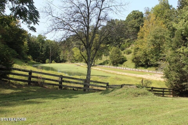 view of gate with a lawn and a rural view