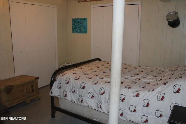 bedroom with multiple closets and wooden walls