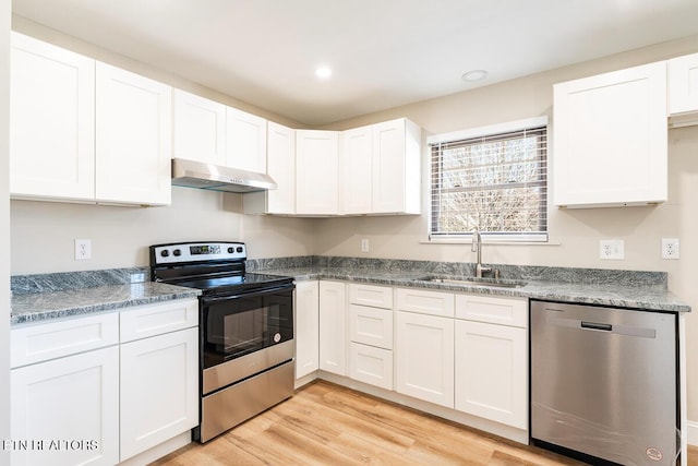 kitchen featuring sink, light hardwood / wood-style flooring, range hood, white cabinetry, and stainless steel appliances