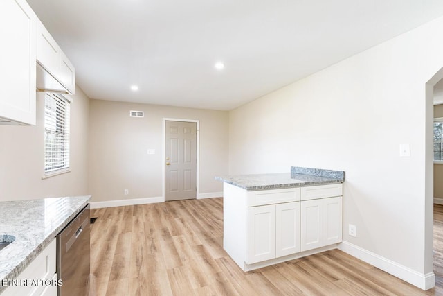 kitchen with light stone countertops, light wood-type flooring, white cabinetry, and stainless steel dishwasher