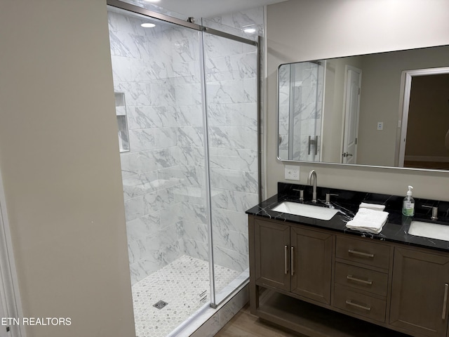 bathroom with hardwood / wood-style floors, vanity, and a shower with door