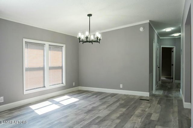 spare room featuring ornamental molding, dark wood-type flooring, and an inviting chandelier