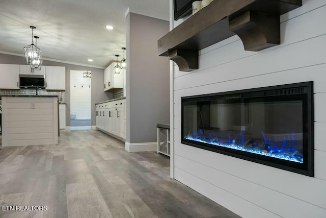 kitchen featuring crown molding, pendant lighting, hardwood / wood-style flooring, white cabinetry, and lofted ceiling