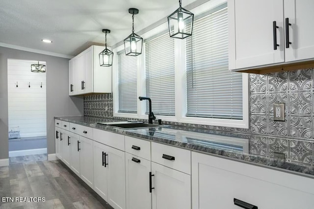 kitchen with dark stone counters, dark wood-type flooring, sink, pendant lighting, and white cabinetry