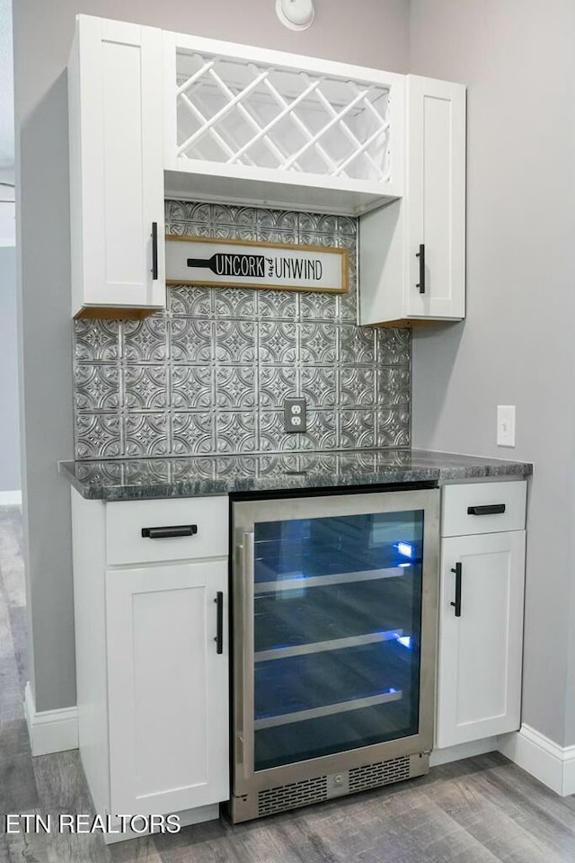 bar with wine cooler, white cabinetry, and decorative backsplash