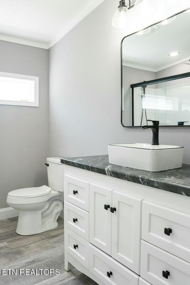 bathroom featuring vanity, crown molding, hardwood / wood-style flooring, toilet, and a shower with shower door