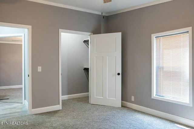 unfurnished bedroom with crown molding, light carpet, and a closet