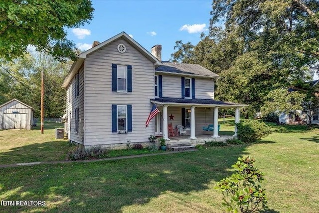 view of front of home featuring covered porch, a front lawn, and a storage unit