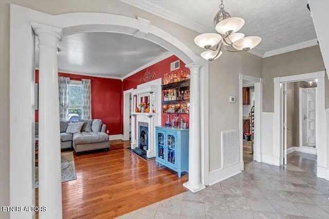 interior space with a chandelier, hardwood / wood-style flooring, decorative columns, and crown molding