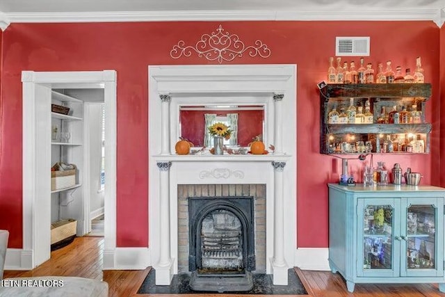 bar featuring built in shelves, crown molding, wood-type flooring, and a brick fireplace