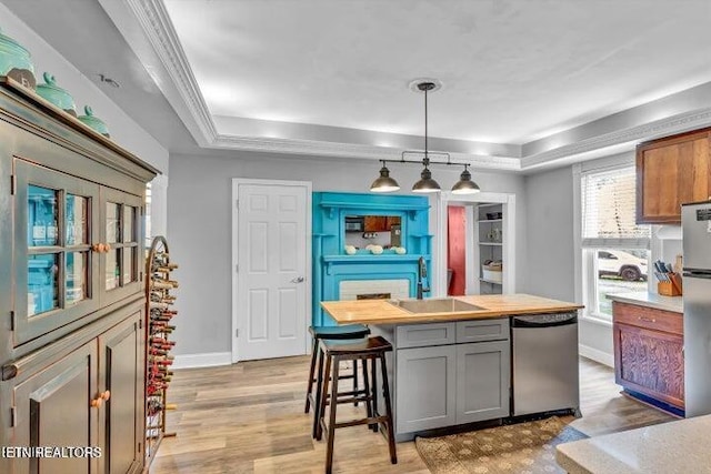 kitchen with sink, gray cabinets, a tray ceiling, a kitchen island, and stainless steel appliances