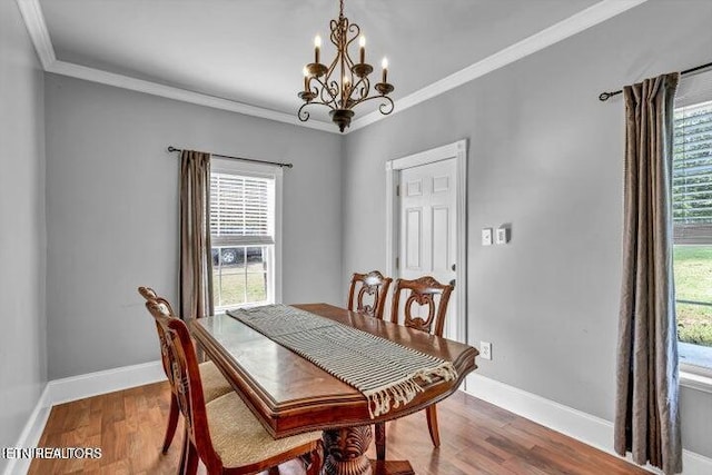 dining area featuring ornamental molding, hardwood / wood-style flooring, and a notable chandelier