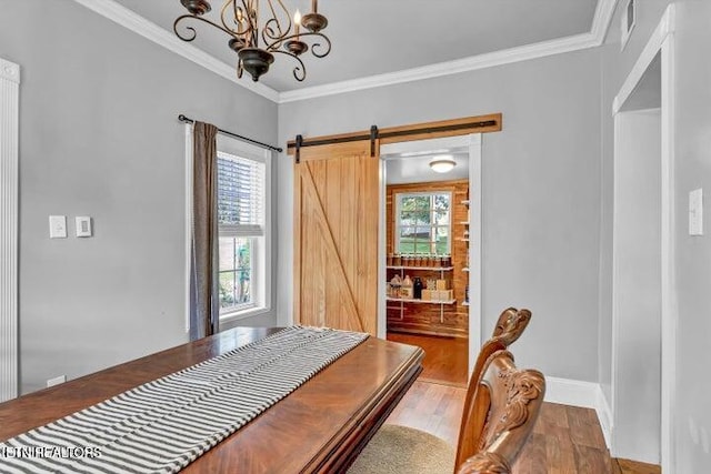 dining room with a barn door, crown molding, light hardwood / wood-style flooring, and a chandelier