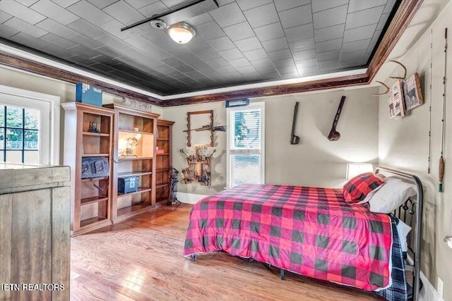 bedroom featuring wood-type flooring, multiple windows, and crown molding