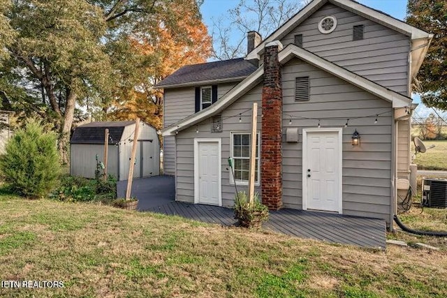 back of house with a storage unit, cooling unit, and a yard