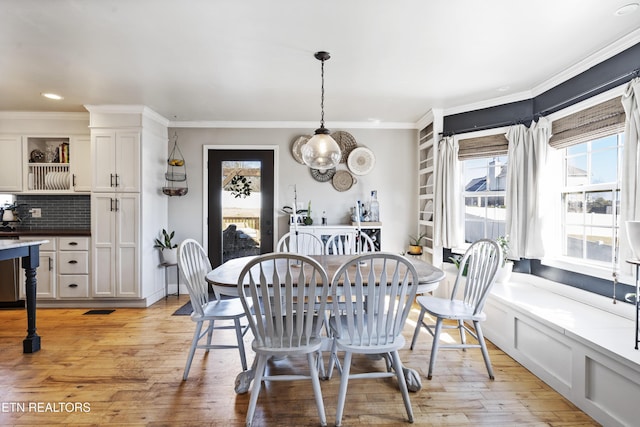 dining space with light hardwood / wood-style flooring and crown molding