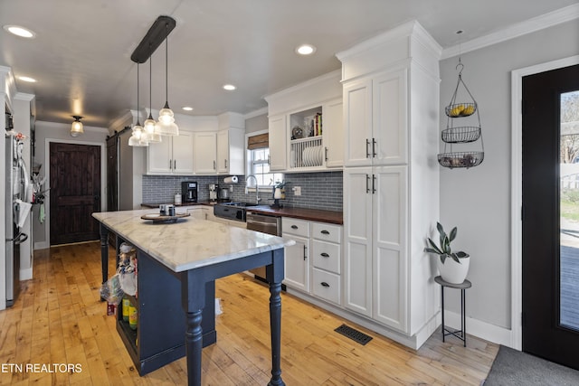 kitchen featuring white cabinets, a kitchen bar, hanging light fixtures, and appliances with stainless steel finishes