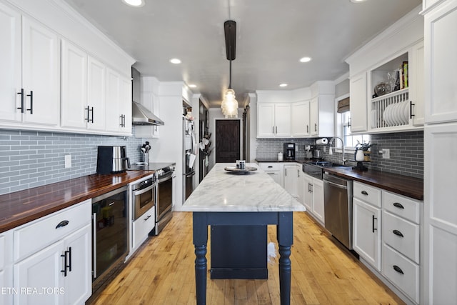 kitchen with stainless steel appliances, sink, a center island, white cabinetry, and hanging light fixtures