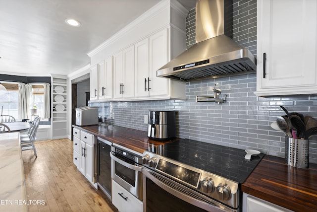 kitchen featuring white cabinets, appliances with stainless steel finishes, decorative backsplash, and wall chimney range hood